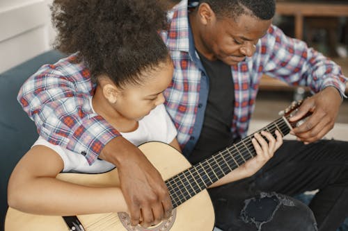 Man Teaching a Girl How to Play Guitar