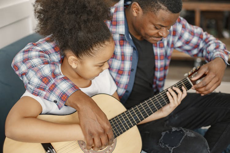 Man Teaching A Girl How To Play Guitar