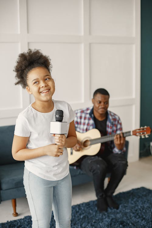 Man Playing Guitar Beside a Girl Holding Microphone and Singing