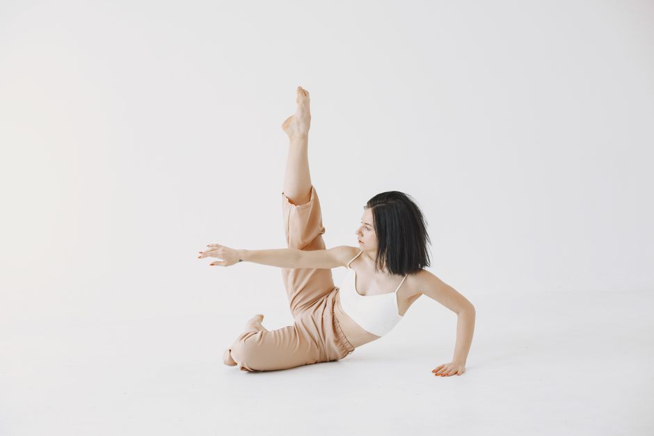 A dancer poses gracefully indoors, emphasizing elegance and flexibility in a modern style.
