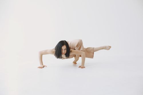 Free A woman demonstrating a challenging yoga pose in a bright, minimalist studio setting. Stock Photo