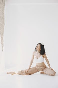 Elegant woman stretching indoors on a bright white floor creating a calm atmosphere.