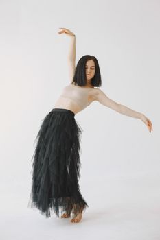 Graceful dancer striking a pose in a tulle black skirt, showcasing elegance and balance.