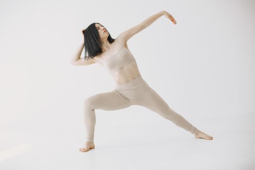 Elegant woman practicing yoga in a serene indoor setting, emphasizing fitness and flexibility.