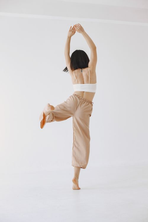 Free Elegant dance pose of a woman captured in a minimalist setting, showcasing movement and grace. Stock Photo