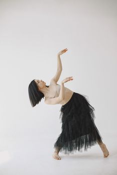 Graceful contemporary dancer posing barefoot in a flowing black skirt.