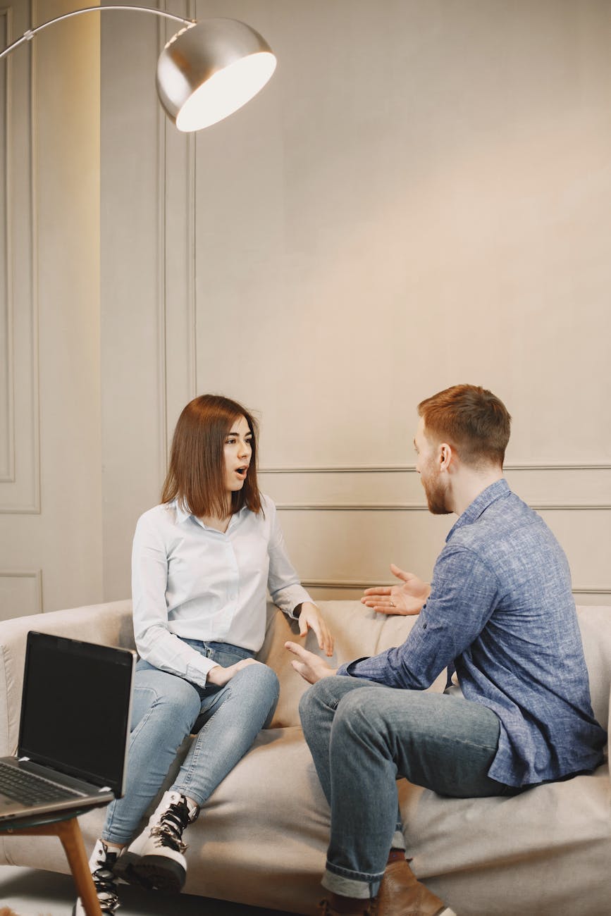 Close-Up Shot of a Man and a Woman Talking while Sitting on a Couch