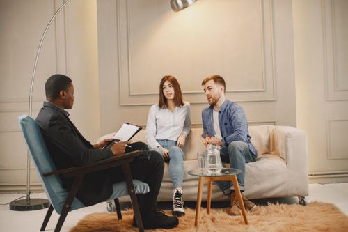 Free A realtor meeting with a couple to discuss real estate options. Modern indoor setting with a casual atmosphere. Stock Photo