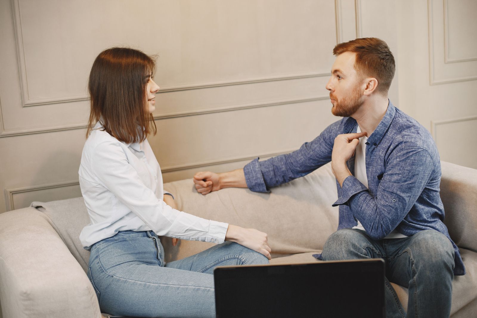 Two people talking while seated on a sofa