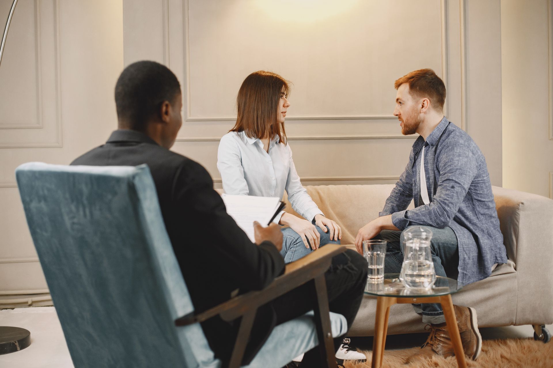 Couple in a counseling session with a therapist in a modern and cozy setting.