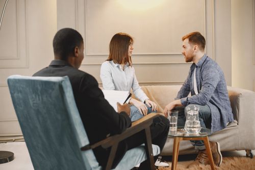 Free Couple in a counseling session with a therapist in a modern and cozy setting. Stock Photo