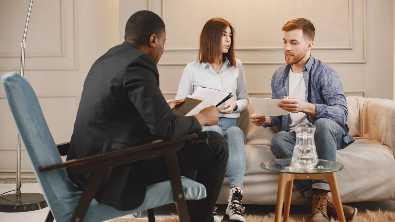 A counselor meeting with two clients in a warm, comfortable therapy office