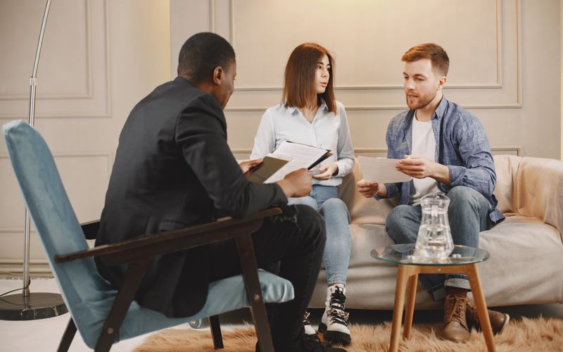 A counselor meeting with two clients in a warm, comfortable therapy office
