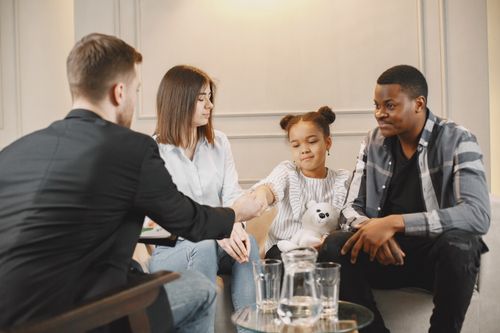 Free A family in a thoughtful counselling session with a professional in a modern setting. Stock Photo