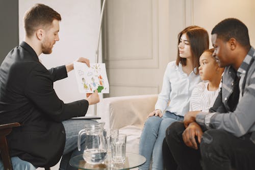 Photo of a Therapist Showing a Drawing to a Family