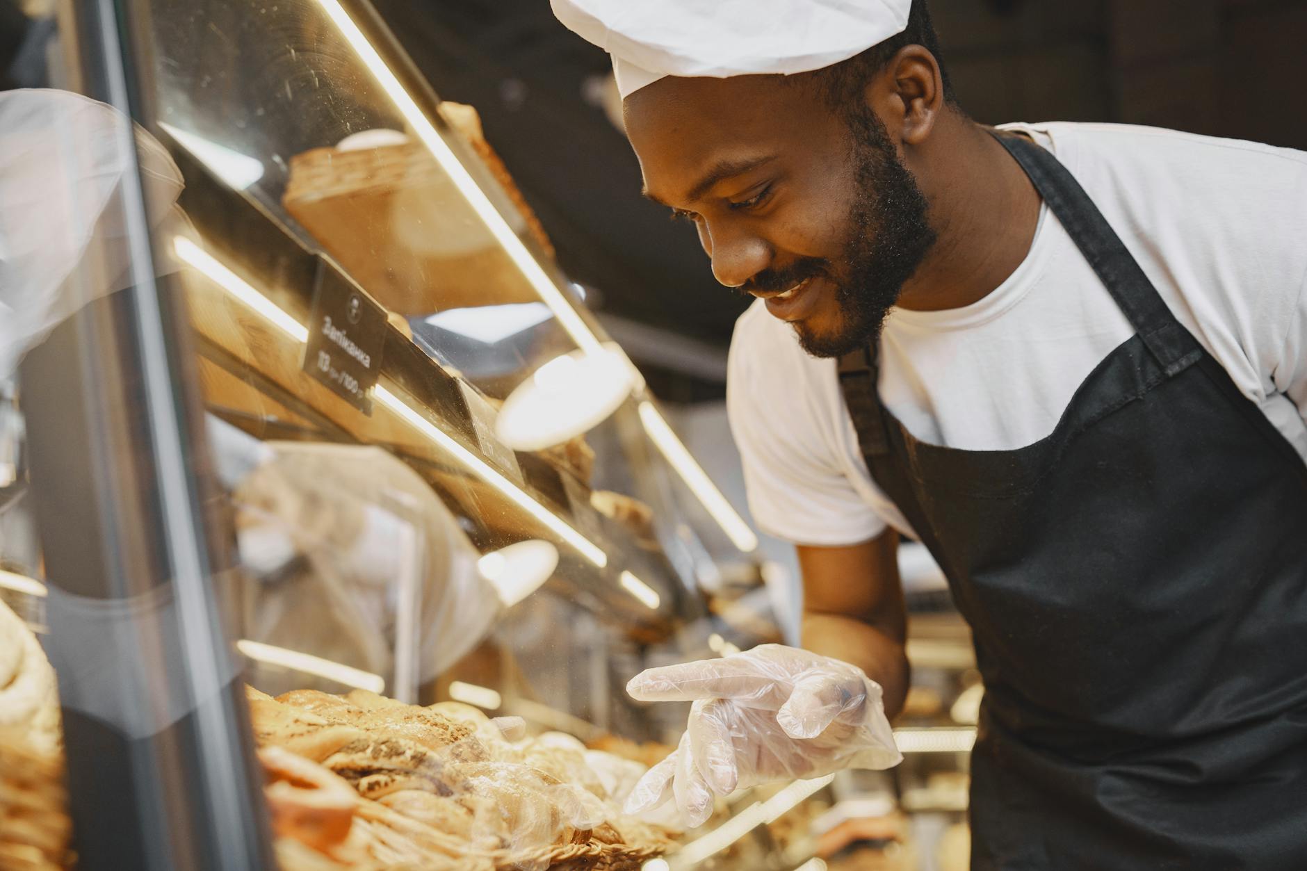 https://www.pexels.com/photo/cook-in-an-apron-pointing-at-a-pastry-product-on-a-display-7447275/