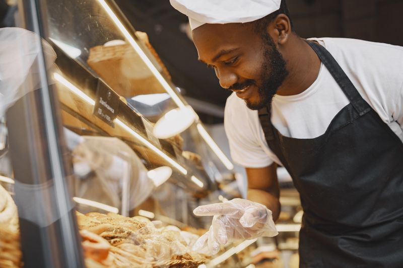 Baker brushing glaze over a freshly baked danish pastry