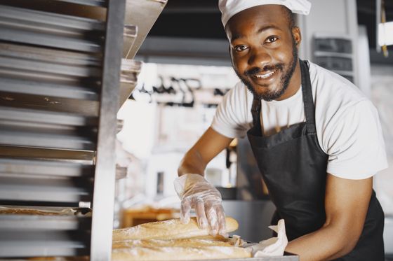 Un boulanger et ses baguettes tout juste sorties du four