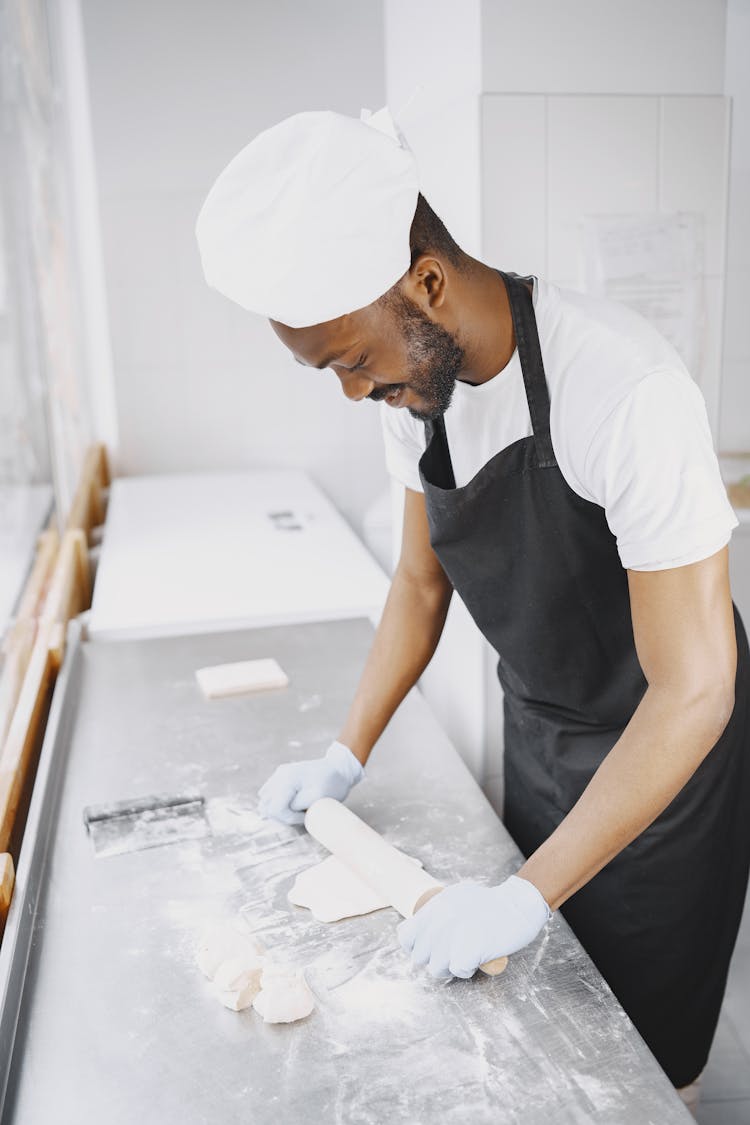 A Baker Rolling Dough With A Rolling Pin