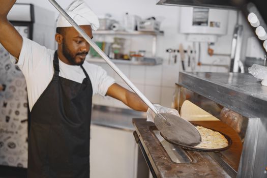 A skilled chef using a pizza peel to place a delicious pizza in a traditional oven.