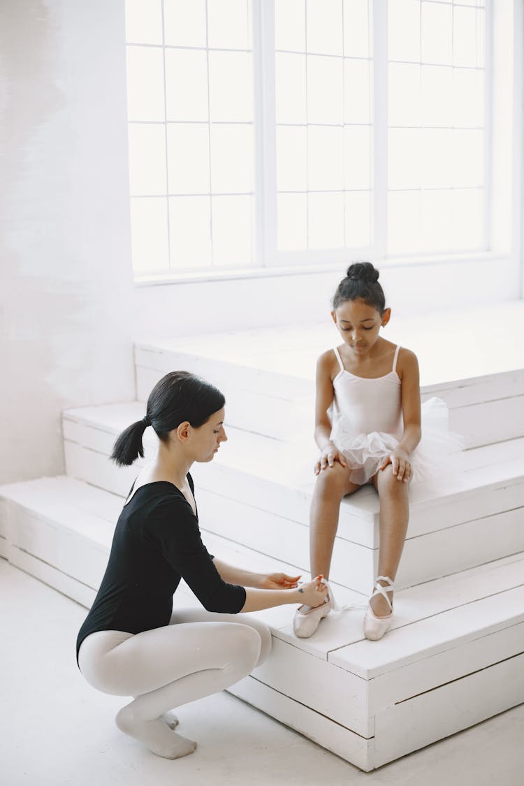 Woman Tying Little Girls Pointe Shoes