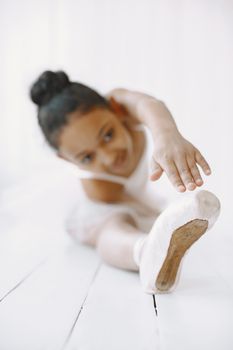 A young girl practicing ballet stretches in a bright dance studio, focused and graceful.