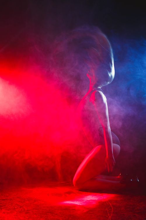 Free Striking image of a person in dramatic red and blue lighting, captured in a misty setting. Stock Photo