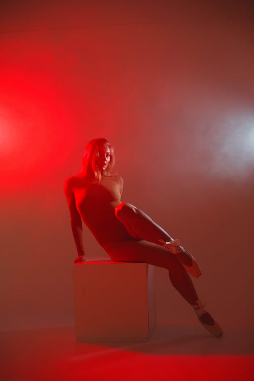 Woman Posing On A Box With Red Smoke On Background