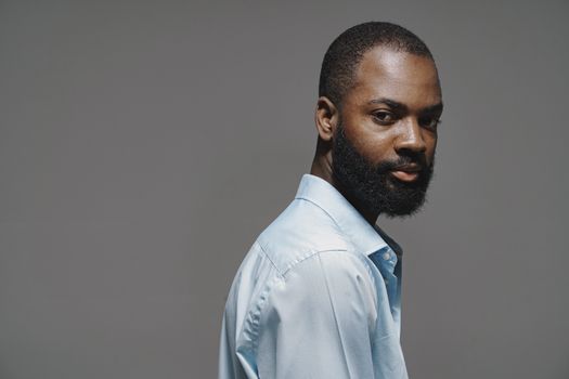 Elegant studio portrait of a well-groomed man in a blue shirt with a contemplative expression.