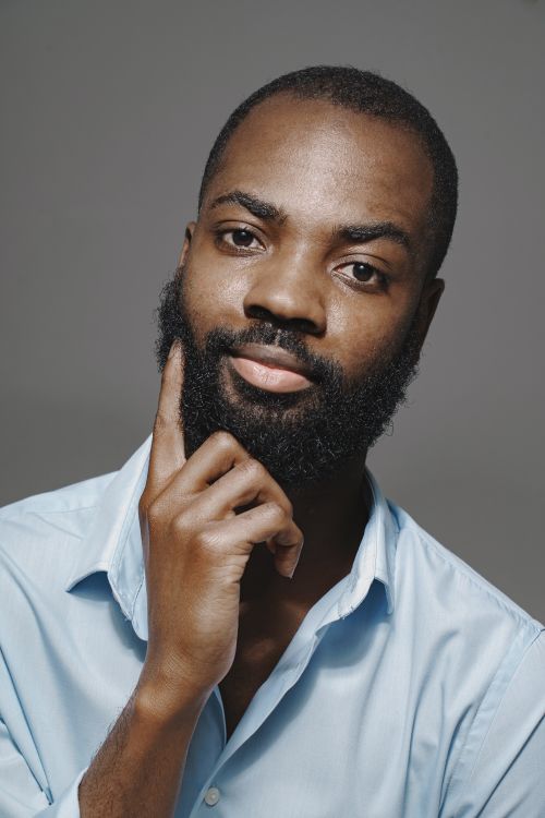 Free Portrait of a thoughtful man with a full beard in a light blue shirt, looking contemplative. Stock Photo