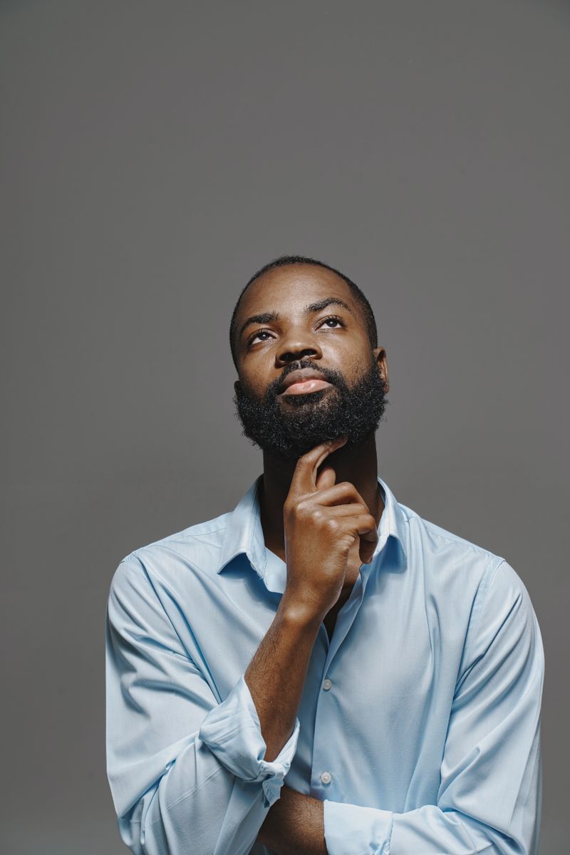 A Black man pauses in a thoughtful, composed moment. Erectile dysfunction is common, often tied to treatable conditions, and worth raising with a clinician.