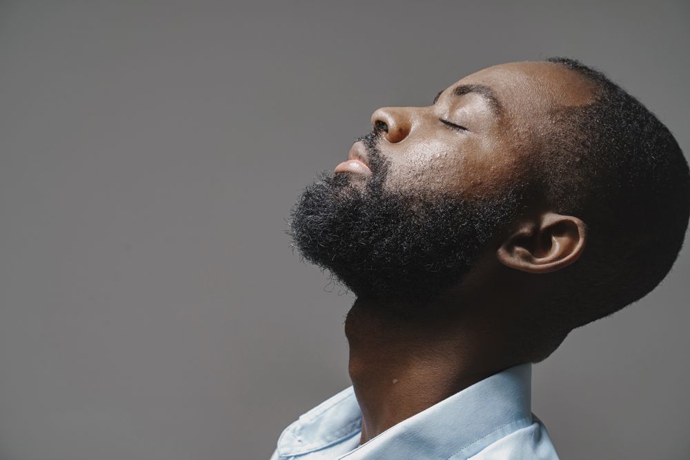 A man with his head tilted back, eyes closed, ready for a shave