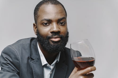 Man In Gray Suit Jacket Holding A Glass Of Red Wine
