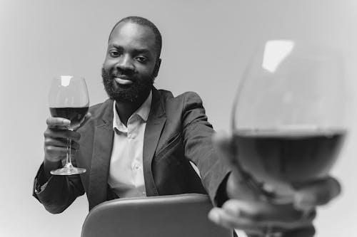 Grayscale Photo of a Man Holding Wineglasses