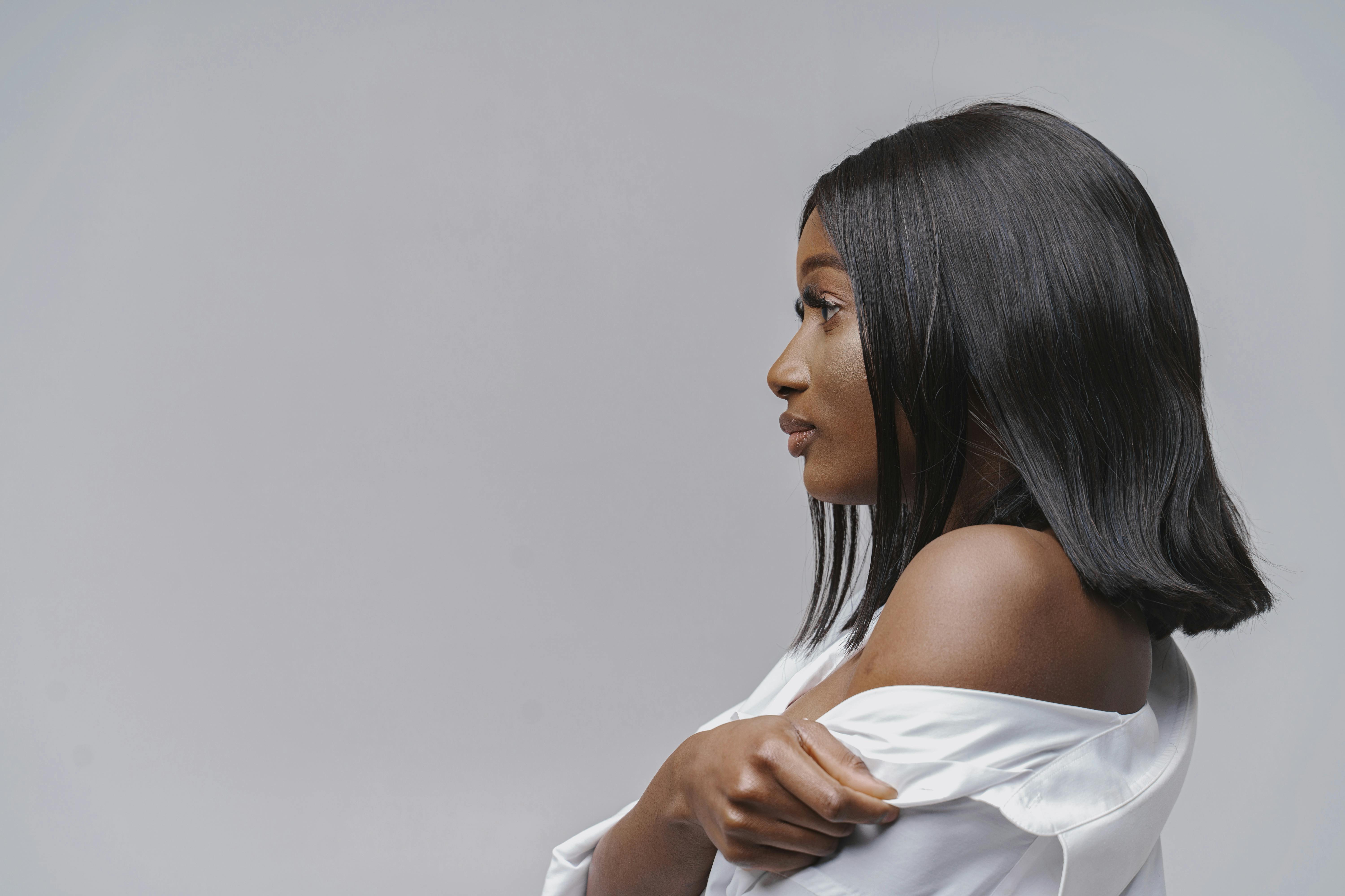 Side profile of a confident black woman in a white outfit against a neutral studio background.