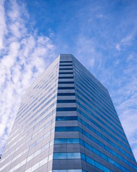 From below exterior of contemporary multistory office building located on sunny street against blue sky with clouds in city center