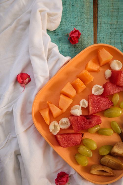Free A vibrant fruit platter with melon, watermelon, and grapes on a rustic table, perfect for a summer picnic. Stock Photo