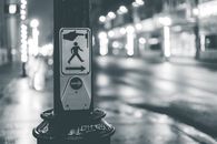 Pedestrian crosswalk button placed near roadway in city in evening time