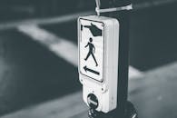 Sign with pedestrian crosswalk call button against road