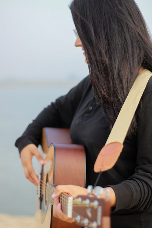 Free A Woman in Black Long Sleeves Playing Guitar Stock Photo