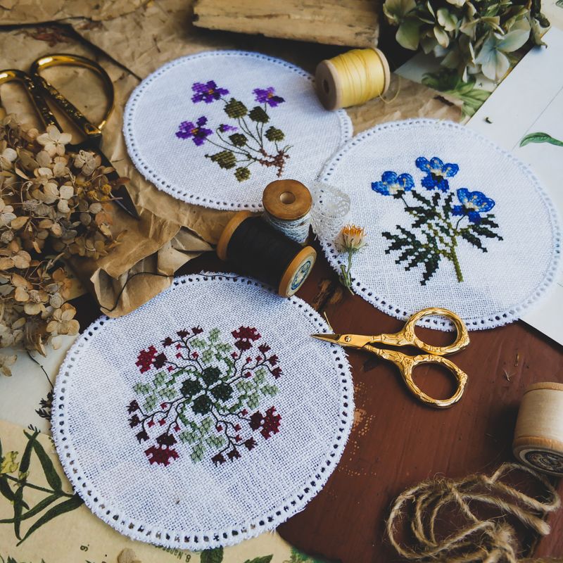 Embroidery kit materials including thread skeins, scissors, and needlework fabric