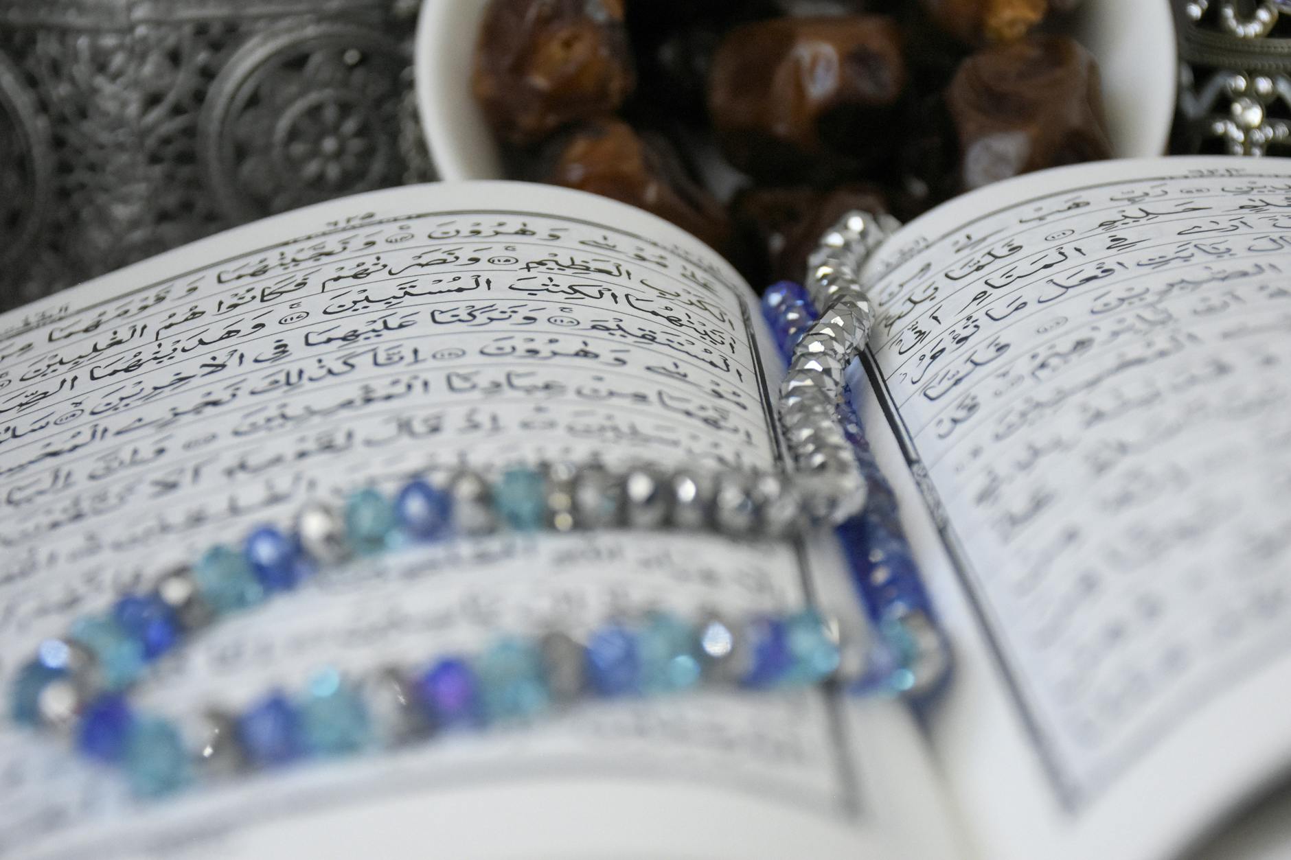 Open Quran with prayer beads and dates symbolizing Ramadan, faith, and spirituality in Islam.
