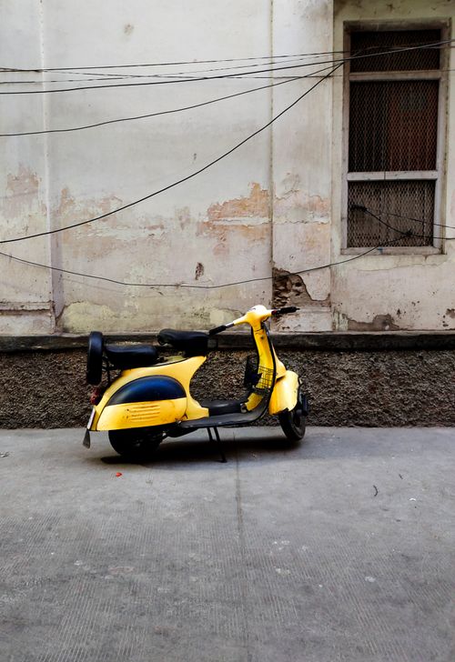 Free Yellow vintage scooter parked against a textured wall in Udaipur, India. Stock Photo
