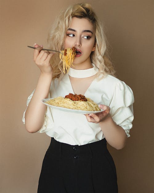 Woman Wearing a White Blouse Eating Pasta