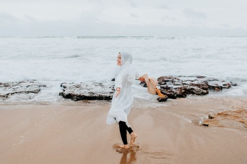 Free Happy woman in white dress and headscarf enjoying a day at the beach. Stock Photo