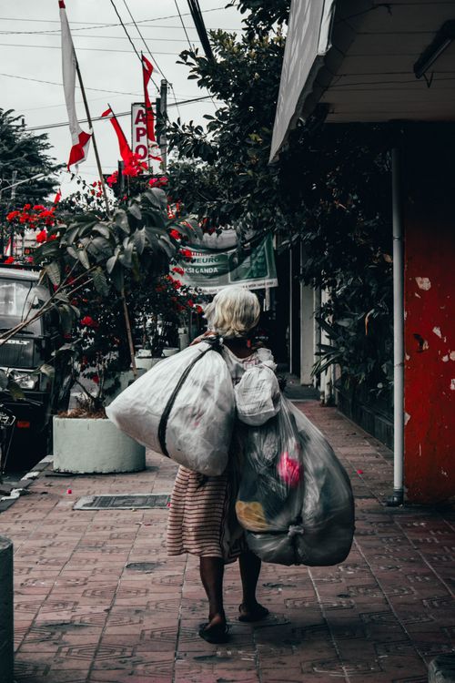 Free An elderly woman with white hair carries bags on a sidewalk in Yogyakarta, Indonesia. Stock Photo
