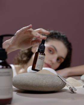 Elegant portrait of a woman holding serum bottle with a blurred background for beauty and skincare concepts.