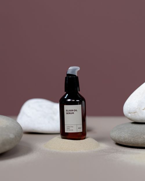 Free A close-up of an elixir oil serum bottle with rocks and sand, perfect for wellness themes. Stock Photo