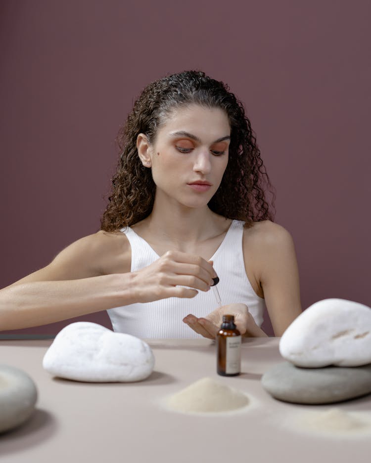 A Woman Putting Serum On Her Hand