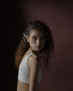 Portrait of a woman with curly hair and barrette in a studio setting.